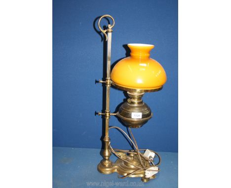 A brass oil lamp converted to electric on adjustable stand with amber glass shade, 24 1/2" tall.