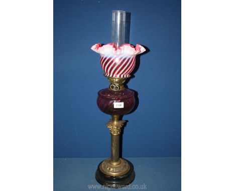 A dual wick brass Corinthian column oil lamp with cranberry glass reservoir and cream swirl shade, with chimney, 28 1/2'' tal