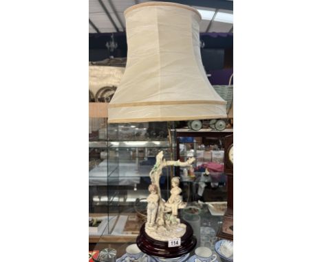 A decorative table lamp with children on a swing by Florence