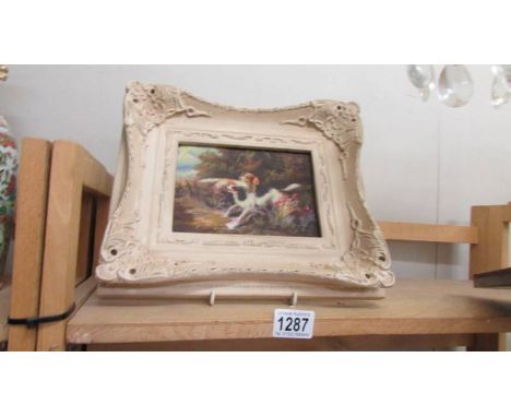 An over painted print of dogs in a white frame.