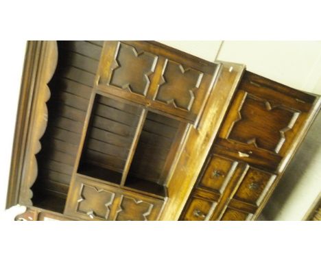 An early 20th Century oak dresser in the Jacobean style, the three tier board plate rack with two cupboard doors over two dra