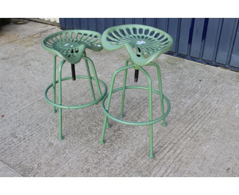 A pair of reproduction tractor seats mounted as stools painted green*