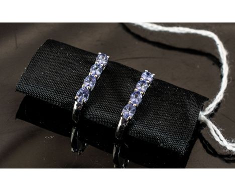 Tanzanite Hinged J-Hoop Earrings, each having four oval cut, bright blue tanzanites, closely set, down the front, a total of 