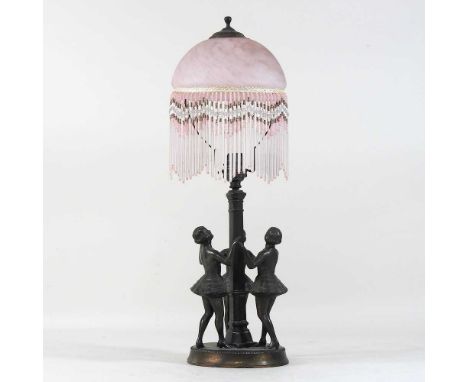 A 1920's spelter figural table lamp, modelled as three ladies dancing around a post, with an opaque pink glass shade, suspend