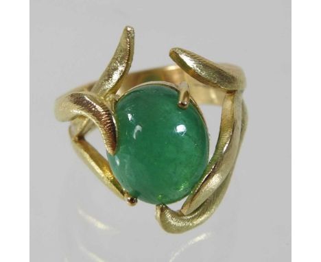 A large 18 carat gold cabochon emerald ring, with an asymmetrical scrolled setting, on a double row textured band, stamped EJ