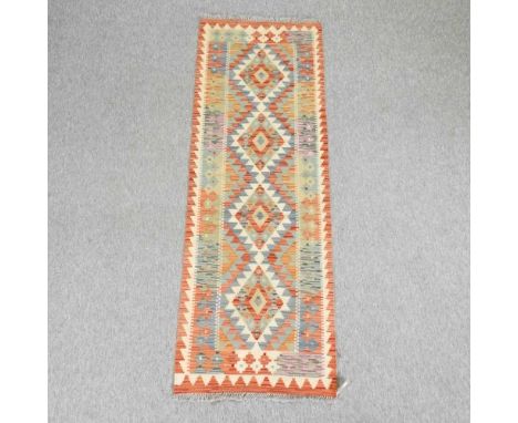 A kelim runner, with geometric design, on an orange ground193 x 65cm