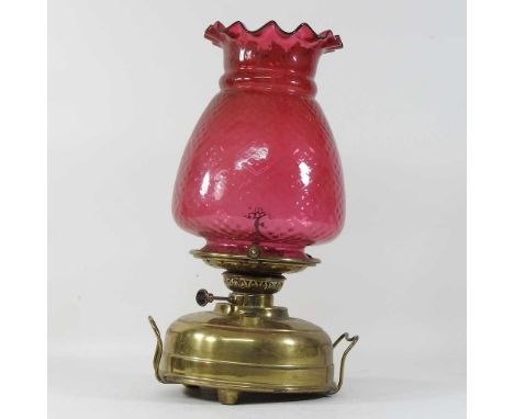 An early 20th century French brass oil lamp, with a mottled cranberry glass shade46cm high