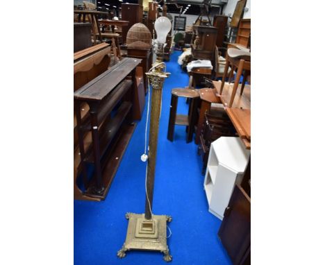 A Victorian standard lamp in brass with lions feet and classical column.