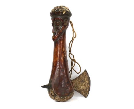 TRIBAL AXE,19th century, an unusual tribal bone axe, carved with the face of a warrior, wearing a hat decorated with small se