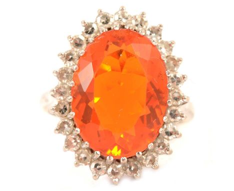 A Mexican fire opal and diamond cluster ring, the oval mixed cut opal 16 x 11.5mm, surrounded by twenty-four 8 cut diamonds c