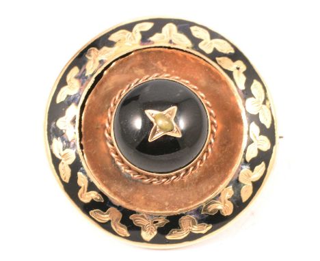 A circular yellow metal mourning brooch with locket back, raised circular cabochon cut black onyx to centre with seed pearl f