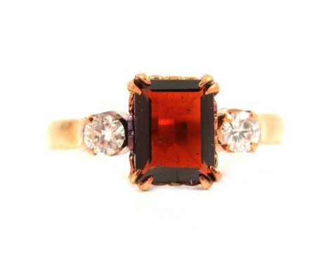 A garnet and diamond three stone ring, the step cut garnet 8.2 x 6.3mm double claw set with a 3.3mm brilliant cut diamond to 