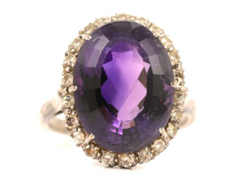 An amethyst and diamond cluster ring, the oval mixed cut amethyst 15.5 x 11.5mm claw set and surrounded by twenty-two 8 cut d