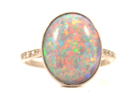 A black opal solitaire ring, the oval cabochon cut opal 13.2 x 10.5mm, collet set in an all white metal mount ring size J, fo