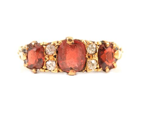 A Victorian garnet and diamond half hoop ring, the three rectangular cushion cut garnets with an orange hue spaced by two pai