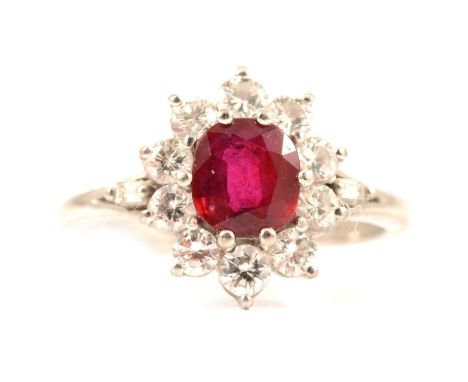 A ruby and diamond cluster ring, the rectangular cushion cut ruby 6 x 5.5mm, claw set and surrounded by ten brilliant cut dia