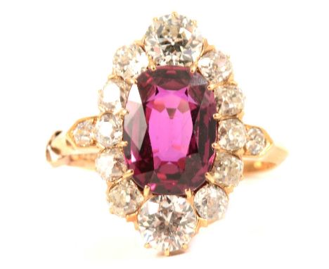 A ruby and diamond cluster ring, the oval mixed cut ruby 11mm x 8mm claw set with one old brilliant cut diamond at either end