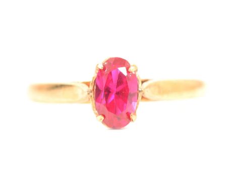A synthetic ruby solitaire ring, the oval brilliant cut 7.1 x 4.3mm synthetic ruby four claw set in unmarked yellow metal mou