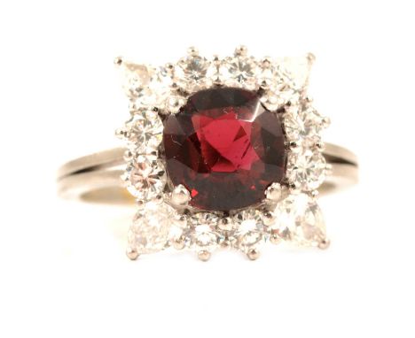 An almandine garnet and diamond cluster ring, the cushion cut almandine garnet surrounded by eight brilliant cut diamonds and