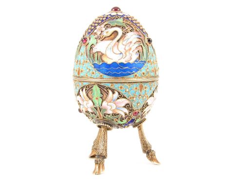 20th century Russian enamelled silver egg shaped trinket pot raised on three hoof legs, four cabochon cut garnets set to the 