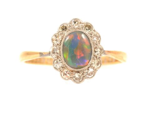 A black opal and diamond cluster ring, the oval cabochon cut opal 6.5 x 5mm surrounded by twelve 8 cut diamonds all milgrain 