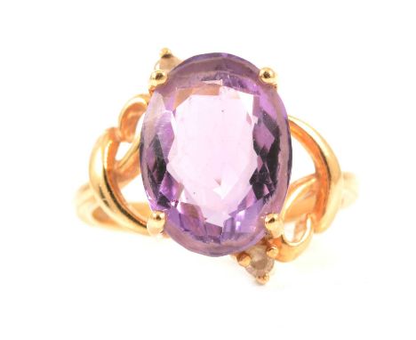 An amethyst dress ring, the oval mixed cut stone 13.5 x 10mm, four claw set in an all yellow metal crossover design mount set