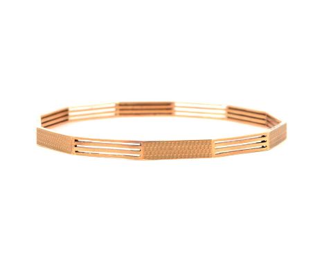 A yellow metal upper arm bangle, 5.5mm wide ten-sided, alternating sections of four bars and engine turning, internal diamete