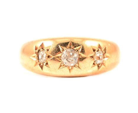 A star gypsy set three stone diamond ring, the old cut diamonds set in an 18 carat yellow gold band tapering from 7.7 to 3.2m