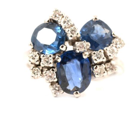A contemporary sapphire and diamond cluster ring, three oval mixed cut sapphires and fourteen brilliant cut diamonds claw set