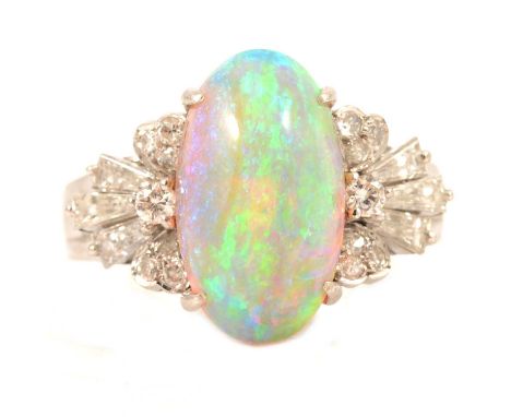 An opal and diamond dress ring, the deep oval cabochon cut opal, 14.5 x 8mm, four claw set in an all white metal mount ring s