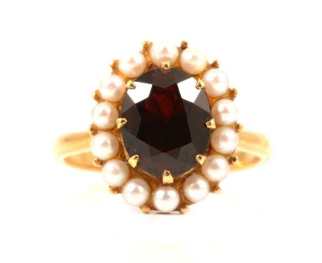 A garnet and pearl oval cluster ring, the oval mixed cut garnet claw set and surrounded by fourteen 2.5mm cultured pearls in 