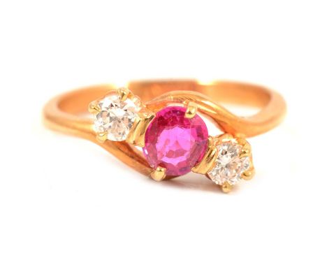 A ruby and diamond three stone crossover ring, the round mixed cut pink stone with one small round brilliant cut diamond to e
