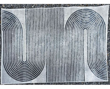 'Think Rugs' - a Modern Designer floor carpet rug. The rug having a grey ground with patterned blue navy decoration. Label to