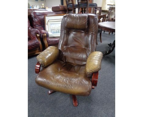 A 20th century beech framed swivel armchair upholstered in a brown button leather. 