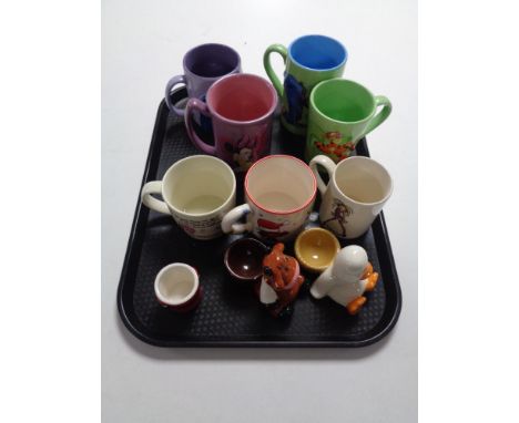 A tray of Disney and other mugs, novelty egg cups 