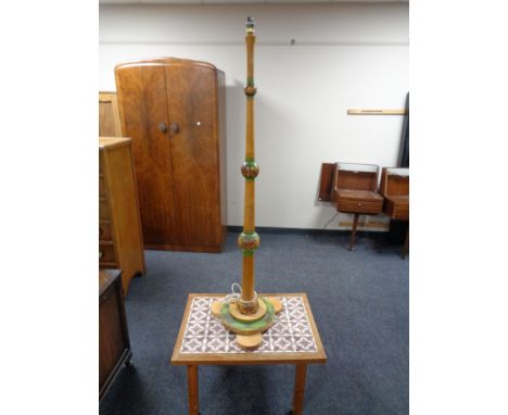 A decorative standard lamp together with a tile topped coffee table.  