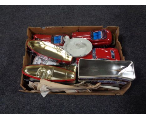 A box containing tins in the form of racing cars, enamel candle stick holder, paper ephemera. 