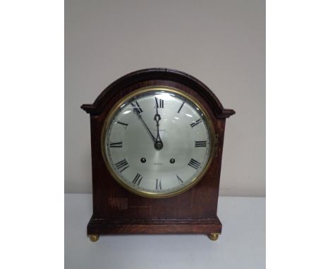 An Edwardian bracket clock with silver dial by Whittaker of Oldham on raised brass feet. 