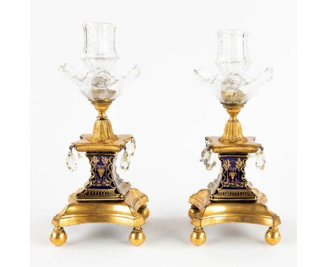 A pair of candlesticks, bronze finished with glass and porcelain. 19th century.&nbsp;Dimensions:(D:10 x W:10 x H:24 cm)