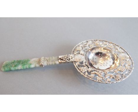 WITHDRAWN A Chinese silver tea strainer with pierced cast decoration and carved jade handle
