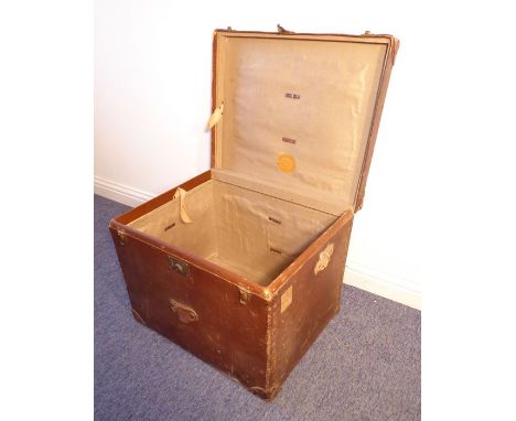 An early 20th century travelling trunk; reinforced with leather corners, single leather handled lid opening to reveal retaile