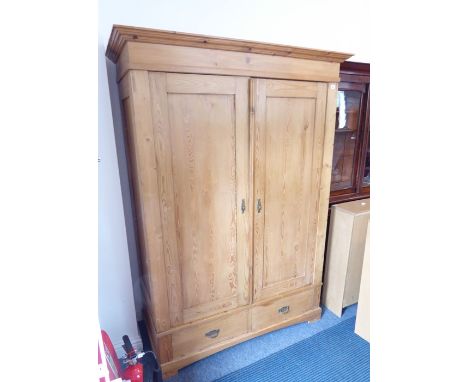 A good pine double wardrobe, cupboard doors above two half-width drawers and raised on bracket feet (129cm wide)&nbsp;