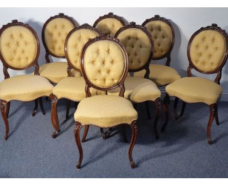 A set of eight mid-19th century walnut button-back upholstered salon chairs; the tightly carved top rails decorated in relief