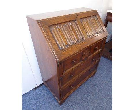 A reproduction oak writing bureau; the sloping fall with linenfold panelling and opening to reveal pigeonholes and drawers ab