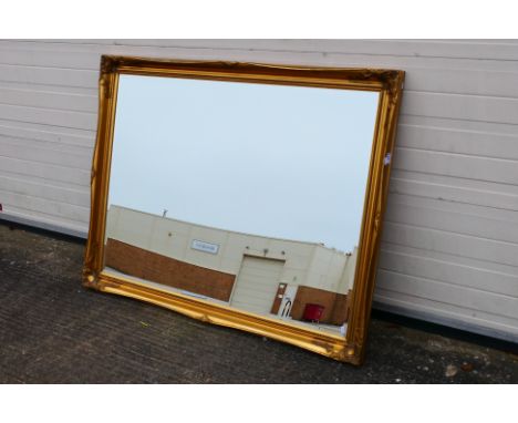 A large, ornately framed, bevel edge wall mirror, approximately 106 cm x 136 cm. [W]