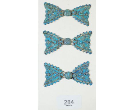 A set of three Chinese white metal and turquoise enamel bow form buckles