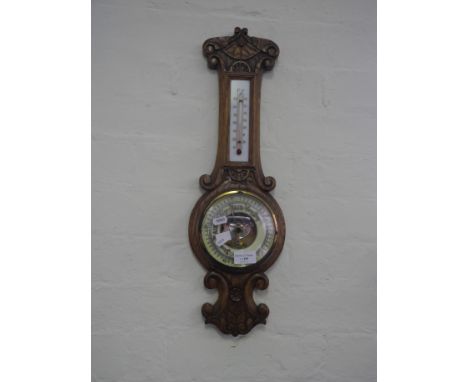 A carved oak wall mounted barometer.
