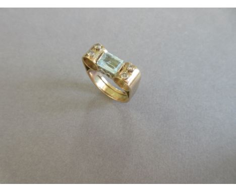 A modern craftsman made aquamarine and diamond ring, the step cut aquamarine horizontally set and held by chenier hoops eithe