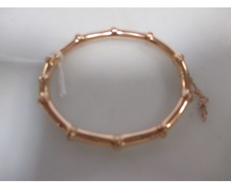 A 15ct faux bamboo style hinged bangle, with safety chain, 10g  