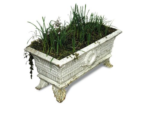 A cast iron garden trough shaped planter, decorated in relief with a fluted body and central wreath, on leaf moulded feet and